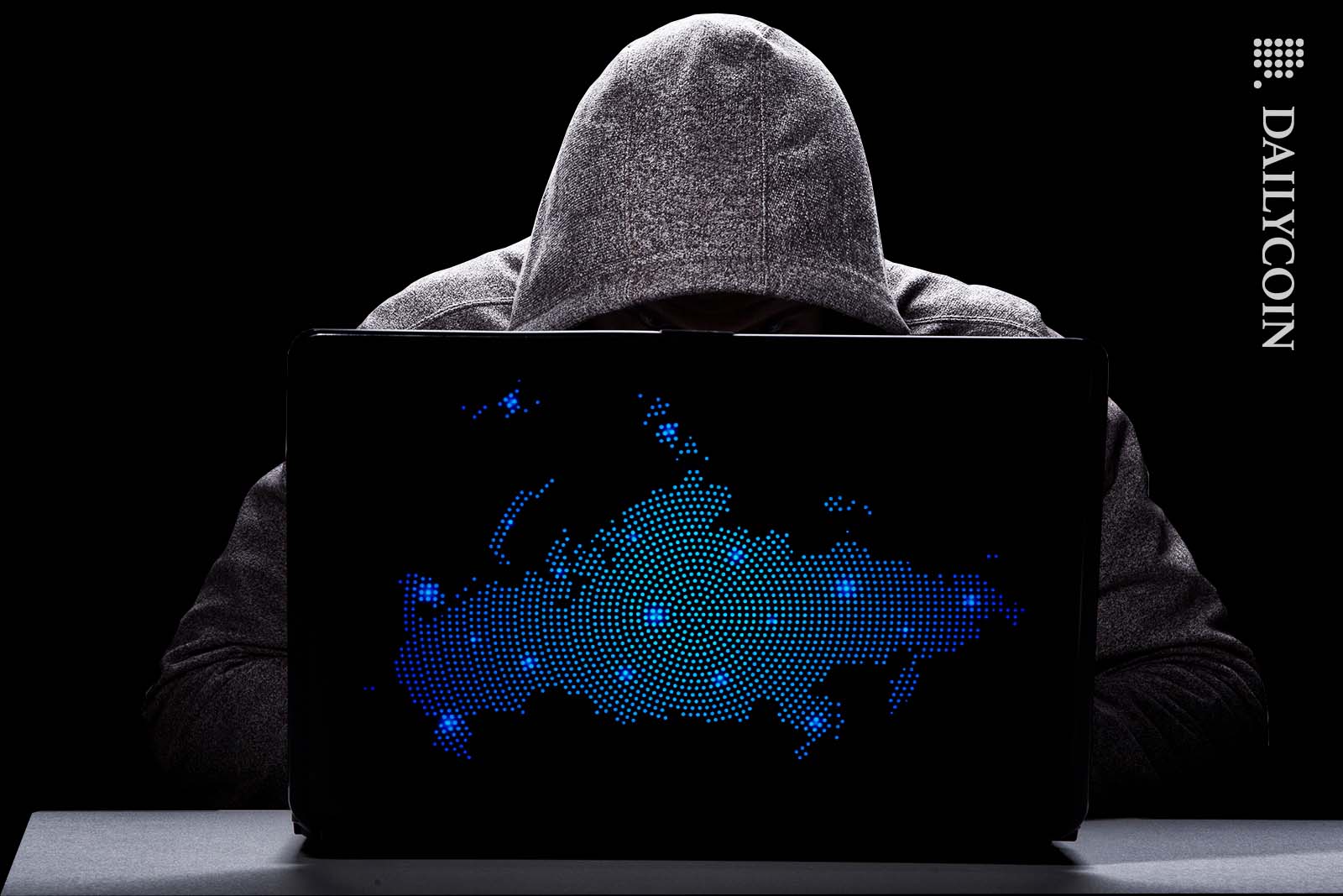 Hacker looking at his laptop with a digital russia map on it.