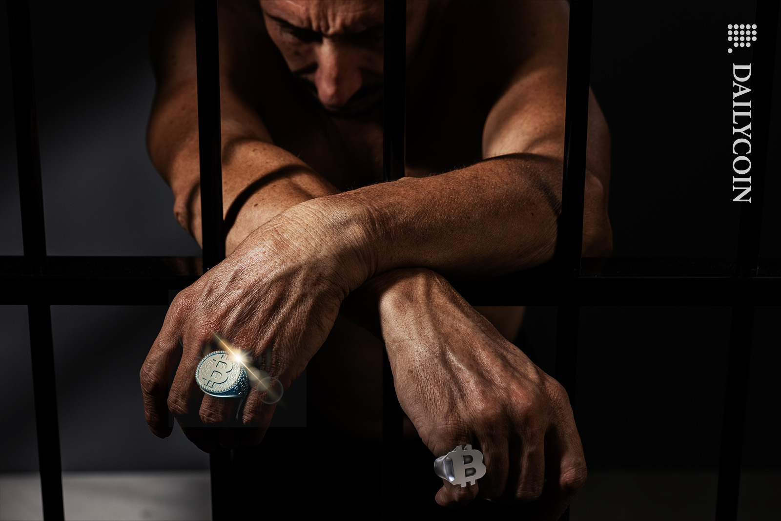 Man in jail being sad, wearing Bitcoin rings.