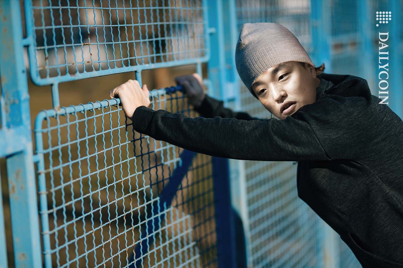 Do Kwon hanging onto a prison fence in Montenegro.