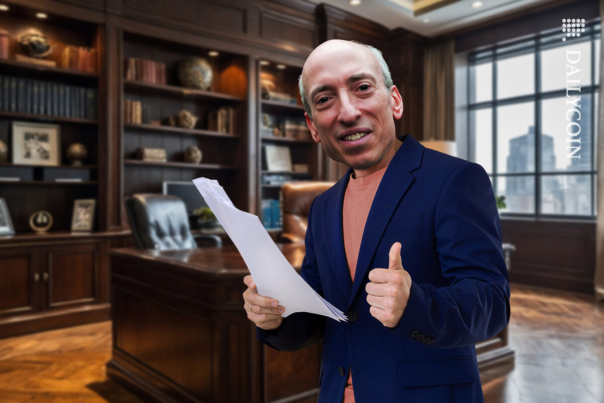 Gary Gensler in his office smiling with documents and a thumbs up.