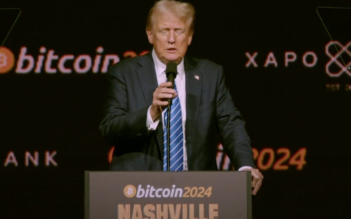 Donald Trump adjusting a microphone to speak at the 2024 Bitcoin conference.