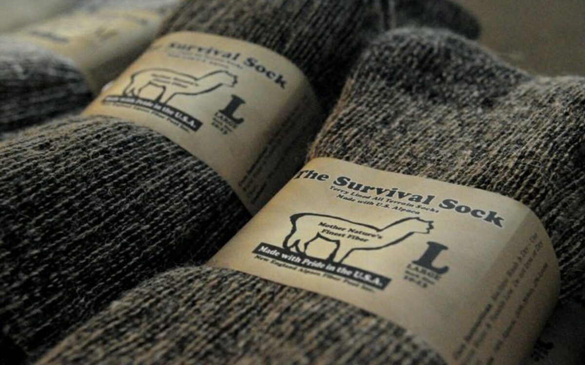 A pair of "Survival Socks" which are made out of alpaca fur. They are a grey color.