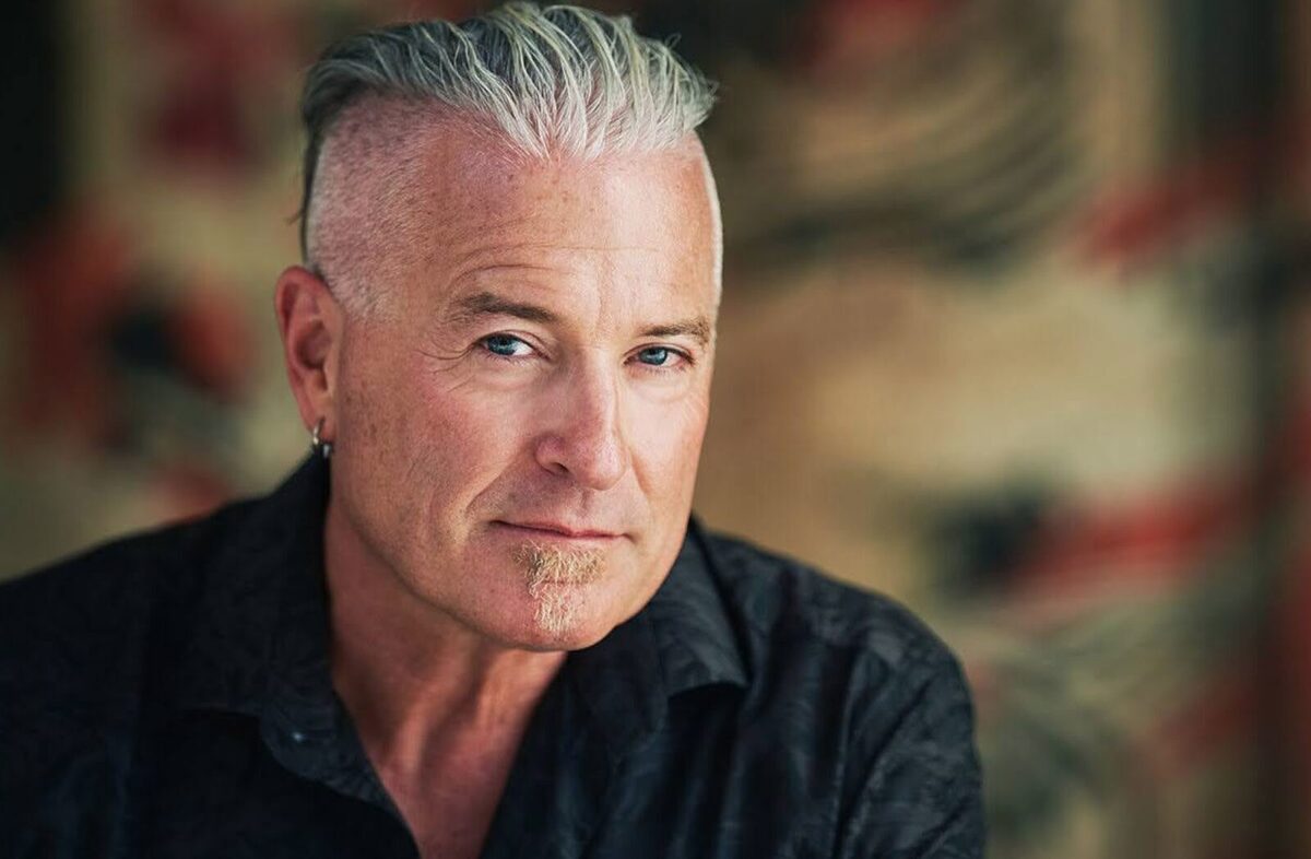 Calvin Ayre looking at the screen. He is wearing a black shirt with a blurred out background.