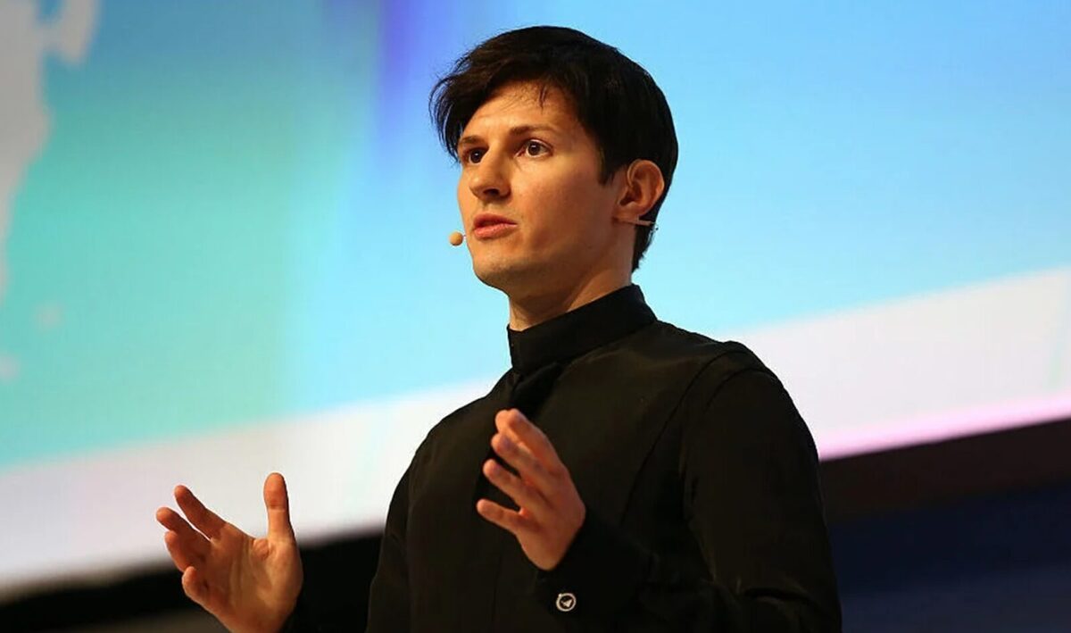 Pavel Durov giving a speech in front of a blue screen in the background.
