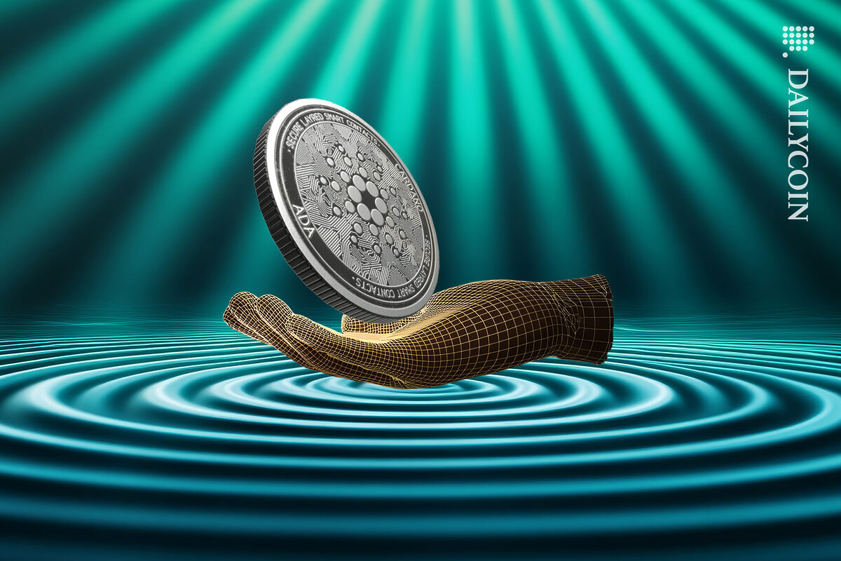 A digital hand holding a cardano ADA coin making a ripple in the ground.